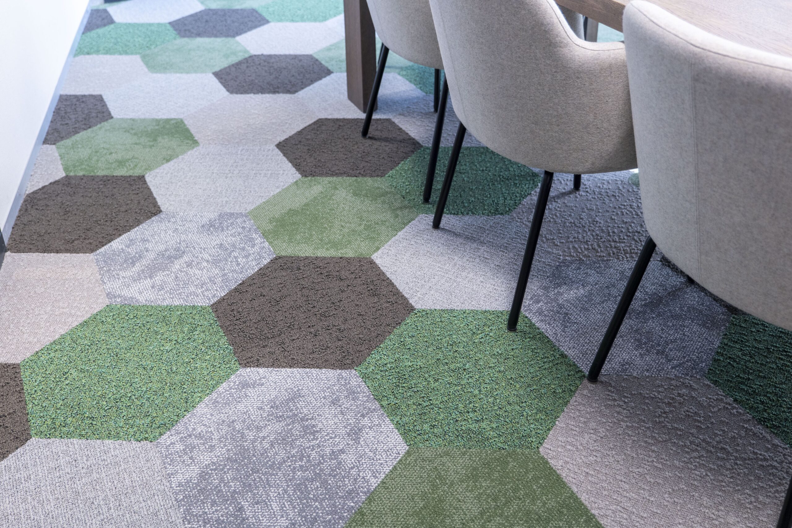 Vergaderruimte met circulaire tapijtvloer in groene en grijze hexagons