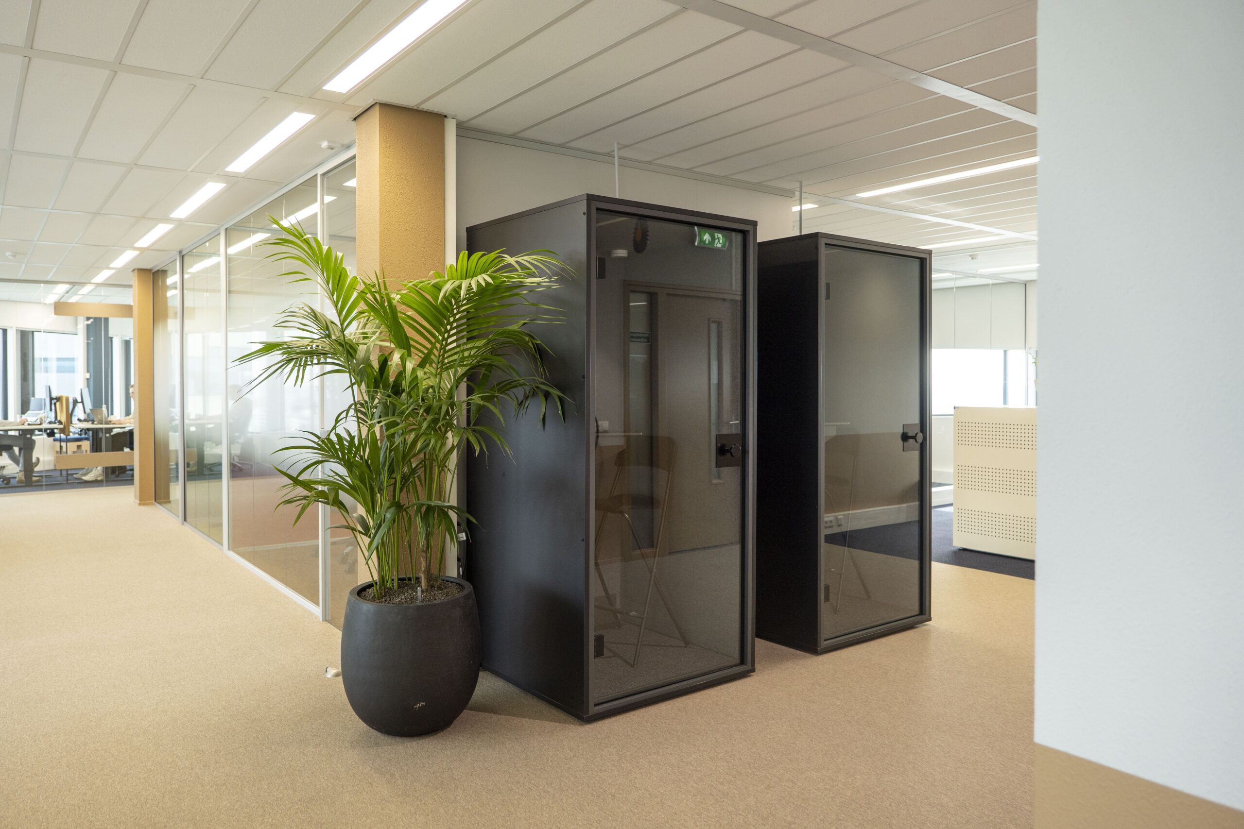 Beige circulaire vloer in kantooromgeving met belcabines bij Witteveen+Bos