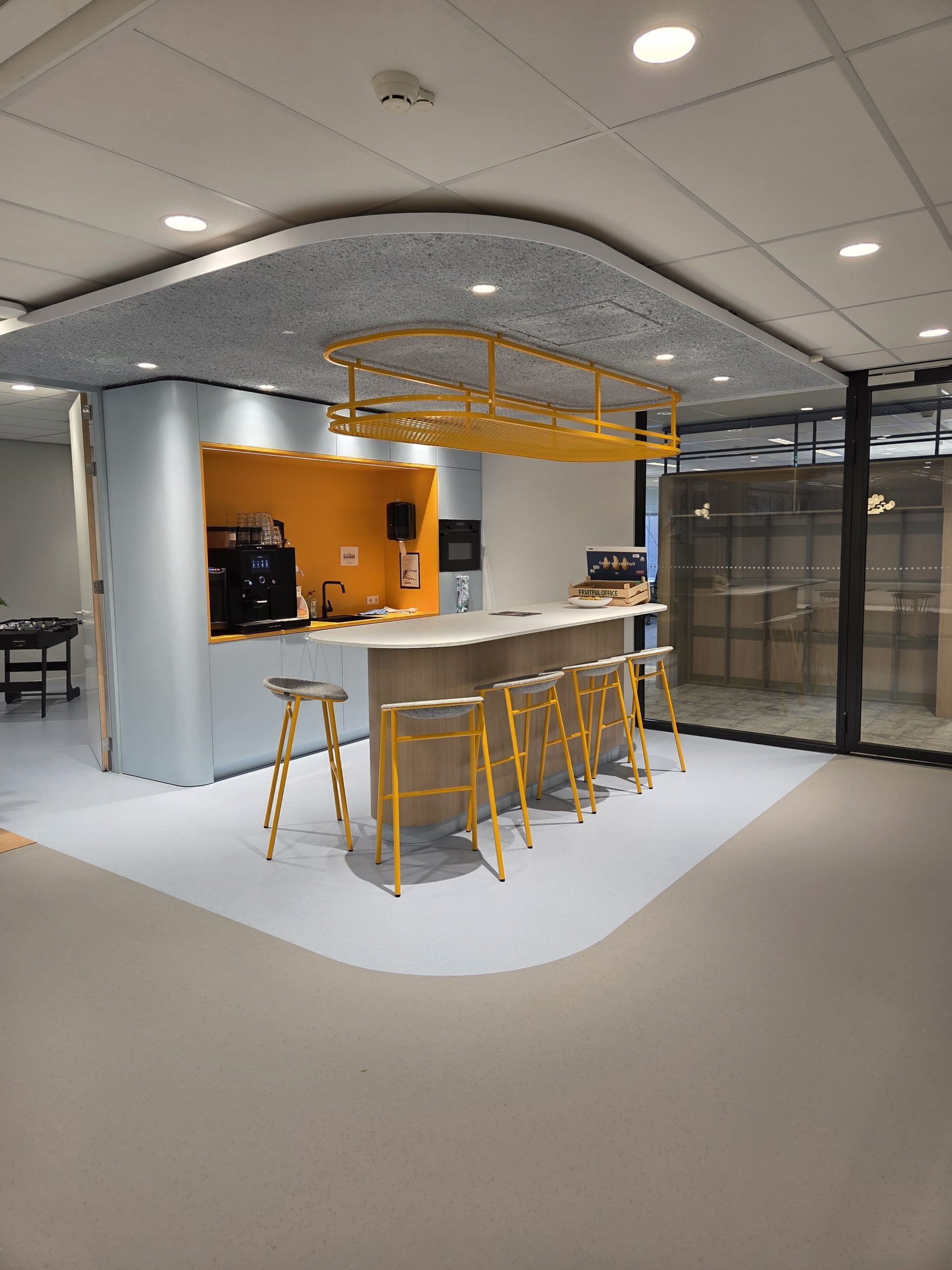 Koffiebar met lichte kantoorvloer en gele interieuraccenten bij KVK